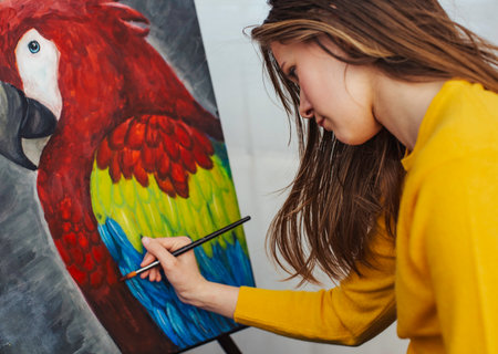 Artist passionately focuses on a detailed, colorful parrot portrait with precision.の写真素材