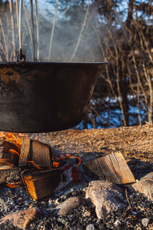 Close-up of an iron pot over a campfire outdoors surrounded by wilderness.の写真素材