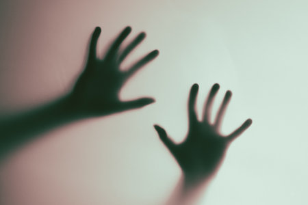 An artistic composition featuring the shadowed silhouettes of hands on a pastel-toned surface. The contrast provides an abstract presentation, evoking mystery and creativity. Perfect for use in conceptual art themes or projects exploring identity and perception.の写真素材