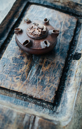 A close-up, detailed view of an antique, carved wooden incense burner resting on a weathered wooden...