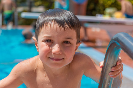 A smiling young boy (5-6) coming out from swimming pool, portrait.の写真素材