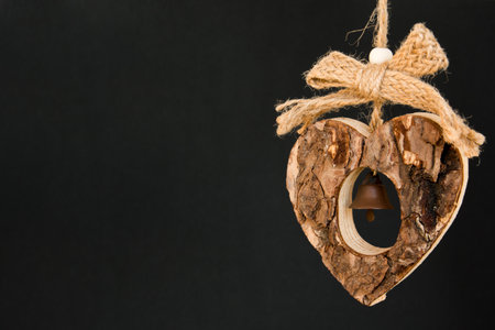 Bark wooden heart on a rope with little opaque brass bell in the middleの写真素材