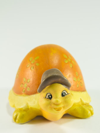 Decorative yellow tortoise ceramic with brown hat against white backgroundの写真素材