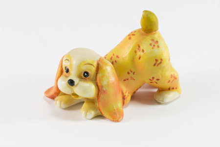 Statuette of dog sitting on white background, ceramic dog figurineの写真素材