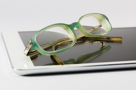 blue reading glasses on digital tablet pcの写真素材