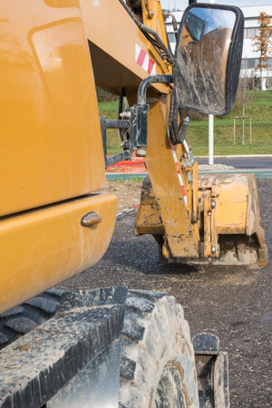 Muddy excavator shovel with rear-view mirror on building siteの写真素材