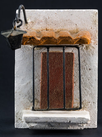 lamppost above door with iron grill, pumice-stone decoration on black backgroundの写真素材