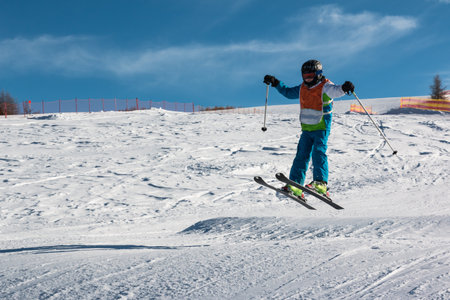 Little skier performs jump in the snow in ski slopeの写真素材