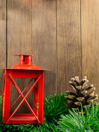 xmas decoration with red candlestick and brown pine cone on wooden backgroundの写真素材