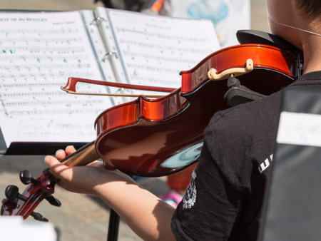 Little Violinist with white Hat during Outdoor Concert, Music Sheet in Backgroundの写真素材