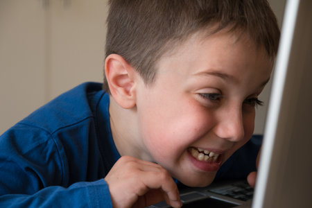 Joking Child in Front of Touch Screen Laptop, tongue stuck outの写真素材