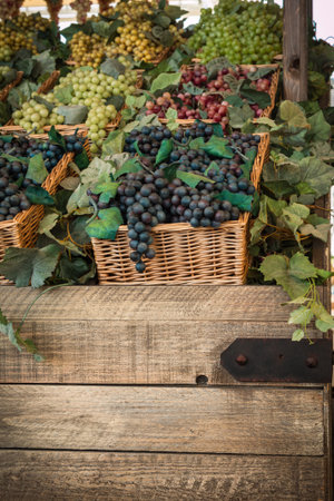 Bunch of Colorful Grapes in Wicker Basket on Wooden Shelf For Saleの写真素材