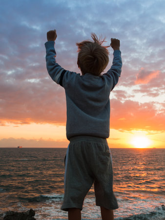 Silhouette of a Child in Front of Sea at Sunset: Winner Attitudeの写真素材