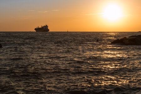 Silhouette of Cargo Boat in Choppy Sea at Sunsetの写真素材