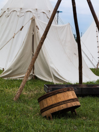 Wooden Pail Overturned on Meadow near White Tentの写真素材
