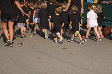 Children with Black Shirt Running in the Park with Young Teacherのeditorial素材