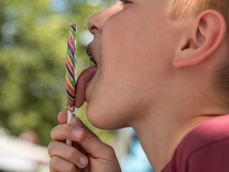 Close up of Eight Years Child Licking Colorful Round Lollipopの写真素材