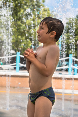 Happy Boy Playing with Water in Fountain in Public Ground in Summer Timeの写真素材