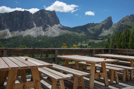 Wooden Tables and Benches Outdoors in Mountain Shelter in Italian Dolomites Alps Sceneryの写真素材