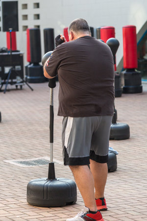 Fat Man in Fitness Class: Workout with Free Standing Boxing Punch Bag and Speed Ball.の写真素材