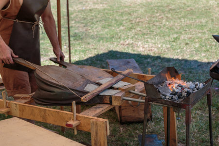 Blacksmith Blows Coals with Bellows, Working Tool.の写真素材