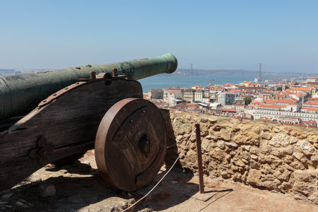 Old Cannon at Castelo de Sao Jorge, Aerial view of Lisbon and 25th April Bridge, Portugalのeditorial素材