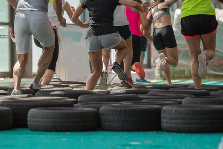 People Running over the Tyre During Fitness Obstacle Exercise.の写真素材
