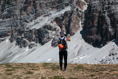 Young Climber Admire Italian Dolomites Alps Scenery and Filming Panorama with Cam.の写真素材