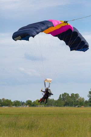 Parachutists: Instructor and Beginner with Blue Parachute preparing for Landing