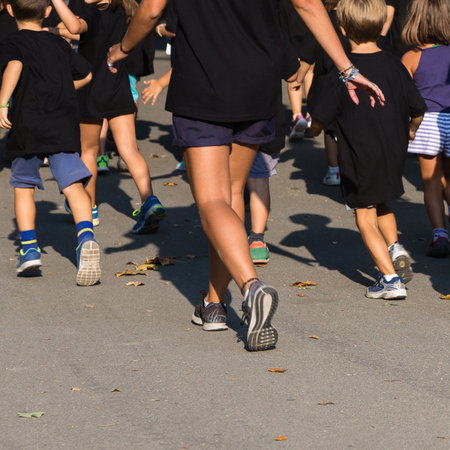 Children with Black Shirt Running in the Park with Young Teacher.の写真素材