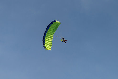 Parachutists: Instructor and Beginner with Green Parachute preparing for Landing