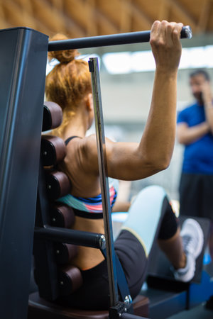 Bodybuilding and Healthy Lifestyle Concept: Girl Having Workout with Fitness Machine in Gym.