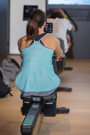 Athletic Girl Exercising on Rowing Machine at Gym: Fitness Equipment.