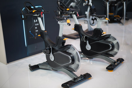 Two Modern Black Spinning Bikes at Gym: Fitness and Workout Equipment.