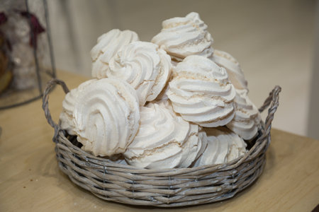 Group of White Meringues in a Wicker Basket.の写真素材