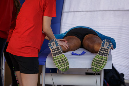 Athlete lying on a Bed while having Legs Massaged after a Physical Sports Workout.の写真素材