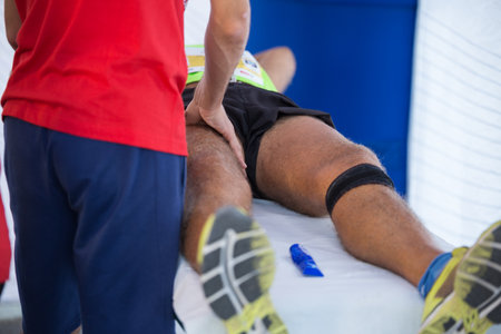 Athlete lying on a Bed while having Legs Massaged after a Physical Sports Workout.の写真素材