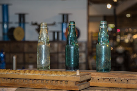 Three Green, Empty and Dirty Glass Bottles on a Wooden Board.の写真素材