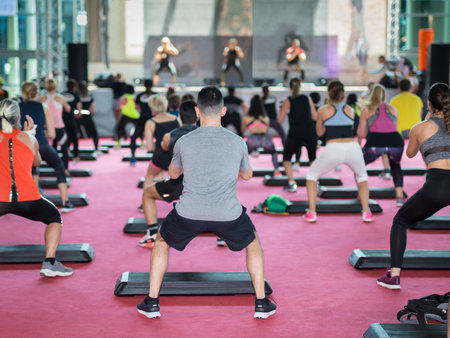 Fitness Workout in Gym: People doing Exercises in Class with Step Platform, Music and Teacher on Stage.のeditorial素材