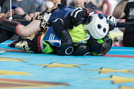 Children Fighting a Boxing Match on the Ground in the Ring with Head and Leg Protections.の写真素材