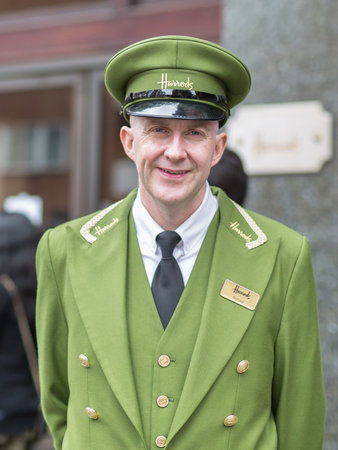 Street Photography: Portrait of Harrods Department Store Receptionist with Green Uniform and Hat in London.のeditorial素材