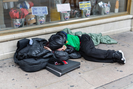 Street Photography: Homeless Sleeping on the Street in front of a Store Window.の写真素材