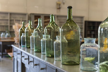 Six Green, Empty and Dirty Glass Bottles over an Antique Wooden Chest of Drawers.の写真素材