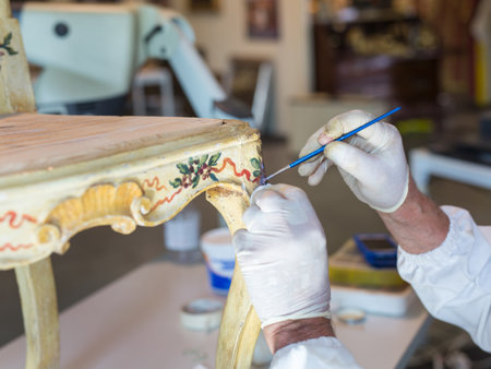 Hands of a Restorer with Gloves and Brush: Working on the Restoration of a Chair.