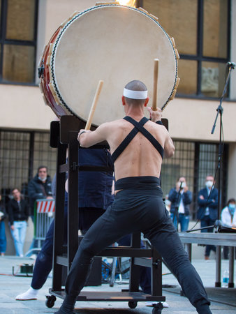 Man with Headband Playing Vertical Drum of Japanese Musical Tradition during a Public Outdoor Event.の写真素材