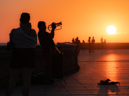 Silhouette of a lone Trumpeter playing his Trumpet at Sunset in a Public Area.の写真素材
