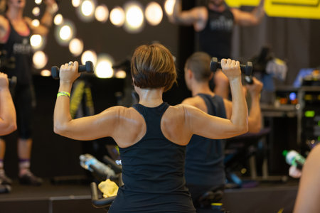 Girl Having Workout at Gym with Indoor Exercise Bike and Small Dumbbells.の写真素材