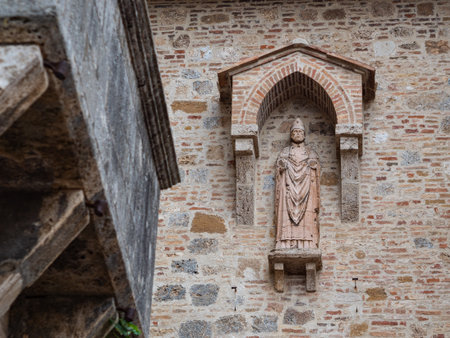 Religious High Relief of a Saint on the External Wall of a Public Building in the Medieval Tuscan Town of San Gimignano - Italy.のeditorial素材