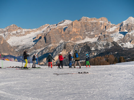 Group of Skiers, adults, teenagers and children ready to face a Descent on the Ski Slope, in the background the Beautiful Italian Alps Mountains.の写真素材