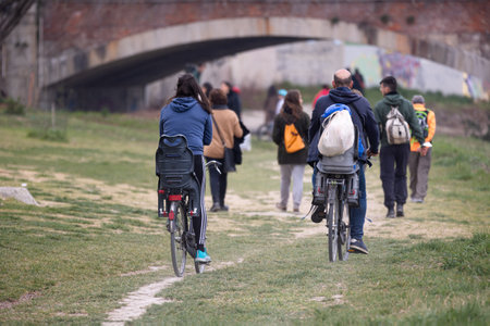 Couple Riding their Bicycle and seat for small children on the Edge of a City River and a Bridge in the background.の写真素材
